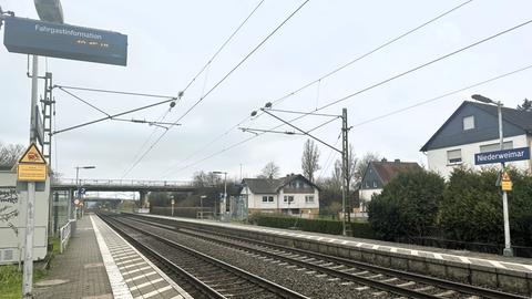 Blick auf Bahngleis und kleinen Bahnhof, im Hintergrund eine Verkehrsbrücke