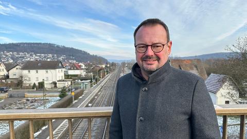 Mann auf Brücke oberhalb von kleinem Bahnhof