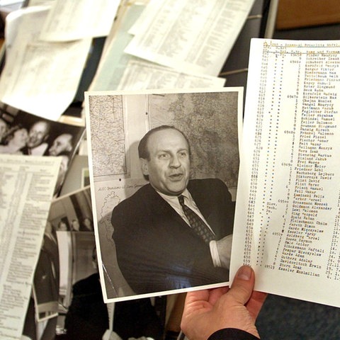 Mit der Schreibmaschine auf Papier getippte Listen, ein Schwarz-Weiß-Foto eines Mannes