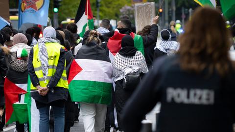 Menschen mit Palästina-Flaggen und Polizei von hinten