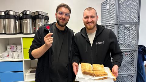 Zwei Männer Mitte 20 halten einen Teller mit Sucuk-Toasts in die Kamera