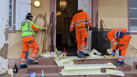 Mitarbeiter der Stadt reinigen den Eingang des Ordnungsamts, nachdem Unbekannte die Fassade und die Tür mit Öl beschmiert haben. 