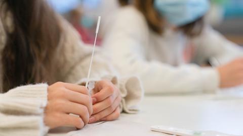 Schülerinnen der Klasse 5c des Matthias-Grünewald-Gymnasiums in Würzburg machen einen Corona-Test: Sie halten Teststäbchen in der Hand.