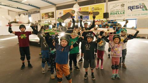 Skate Aid - Kinder halten ihre Skateboards in die Höhe