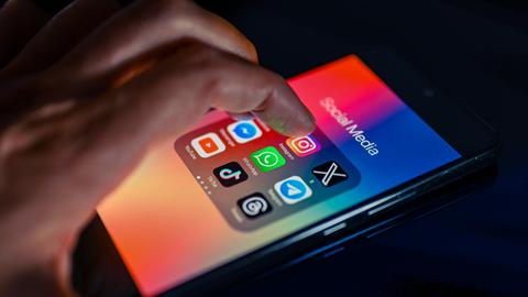 Eine Hand hält ein Smartphone mit Icons mehrerer Social-Media-Apps