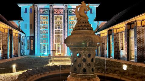 Brunnen mit beleuchtetem historischen Gebäude dahinter