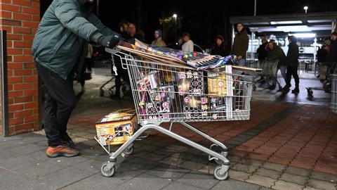 Ein junger Mann schiebt einen Einkaufswagen voll mit Böllern.