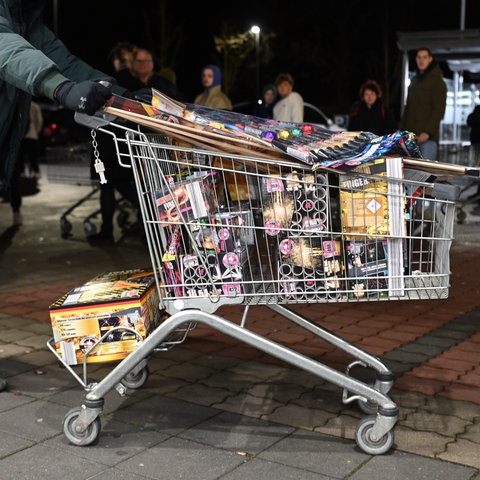 Ein junger Mann schiebt einen Einkaufswagen voll mit Böllern.