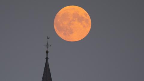 Der Supermond geht hinter der Kirche von Wehrheim im Taunus auf. Durch seine relativ große Nähe zur Erde wirkt der Mond dabei besonders groß.