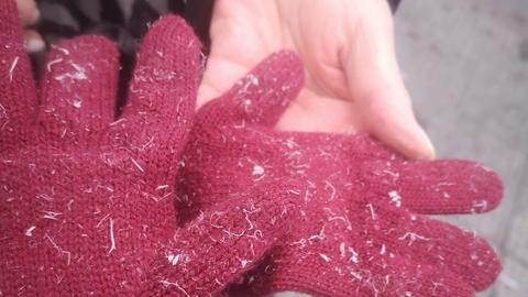 roter Handschuh mit vielen kleinen weißen Plastikfetzen