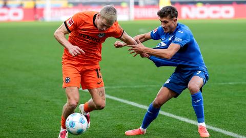 Rasmus Kristensen (im orangenen Eintracht-Trikot) im Zweikampf mit Tom Bischof (im blauen Hoffenheim-Trikot).