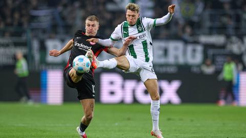 Rasmus Kristensen (Eintracht Frankfurt, schwarzes Trikot) und Robin Hack (Borussia Mönchengladbach, weißes Trikot) im Kampf um den Ball.