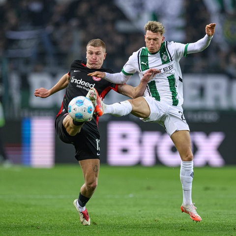 Rasmus Kristensen (Eintracht Frankfurt, schwarzes Trikot) und Robin Hack (Borussia Mönchengladbach, weißes Trikot) im Kampf um den Ball.