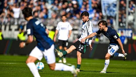 Mehmet Aydin (weißes Schalke-Trikot) im Zweikampf mit Kilian Corredor (blaues Darmstadt-Trikot).