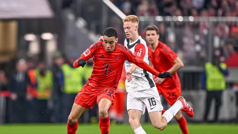 Jamal Musiala (rotes Bayern-Trikot) und Hugo Larsson (weißes Eintracht-Trikot) im Zweikampf. 