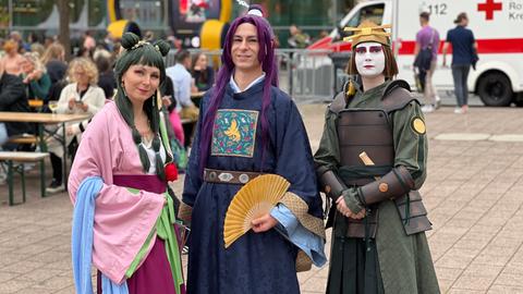 Das Bild zeigt drei Cosplayer auf der Buchmesse 2024, eine Frau und zwei Männer. Sie tragen von traditionell japanischer Kultur inspirierte Kleidung und halten Fächer in den Händen. 