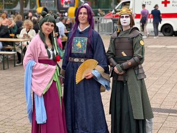 Das Bild zeigt drei Cosplayer auf der Buchmesse 2024, eine Frau und zwei Männer. Sie tragen von traditionell japanischer Kultur inspirierte Kleidung und halten Fächer in den Händen. 