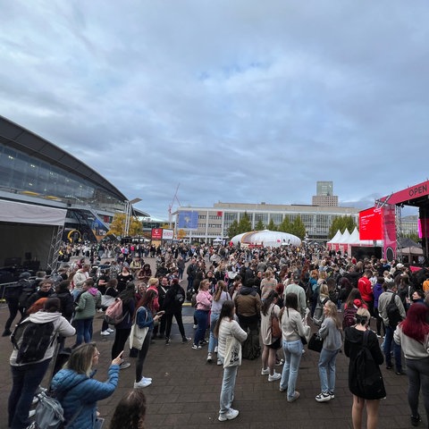 Das Bild zeigt die Agora der Frakfurter Buchmesse. Viele Menschen haben sich vor einer Open-Stage-Bühne auf dem Außengelände versammelt.