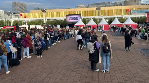 Das Bild zeigt Menschen, die für Signierstunden mit Autoren im Außenbereich der Frankfurter Buchmesse anstehen. Es haben sich mehrere lange Schlangen gebildet.