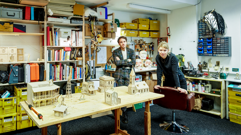 Die Theaterschaffenden Jost von Harlessem und Hanke Wilsmann in ihrem Atelier umgeben von Büchern, Werkzeugen und Modellen.