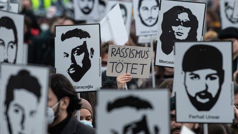 Mit Plakaten und Bildern der Ermordeten erinnern Teilnehmer einer Gedenkveranstaltung an die Opfer des rassistischen Anschlags. 