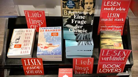 Das Bild zeigt einen Tisch in einer Buchhandlung. Zu sehen sind verschiedene Bücher, die unterschiedlich aufgestellt und gestapelt sind.