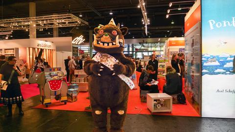 Das Bild zeigt einen Stand auf der Frankfurter Buchmesse. Davor steht ein sogenannter Walking Act, der die Kinderbuchfigur Grüffelo darstellt.