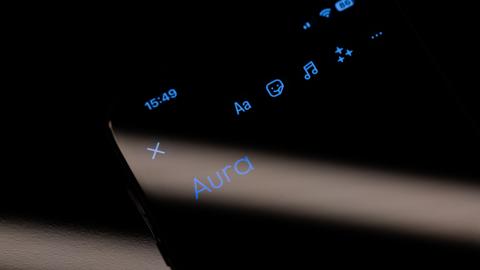 Das Wort "Aura" ist auf dem Display eines Smartphones zu sehen. 