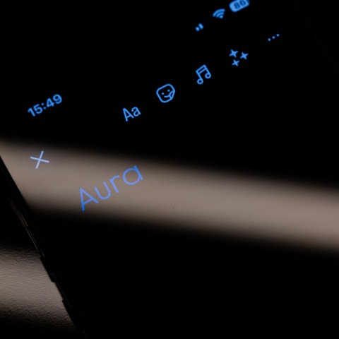 Das Wort "Aura" ist auf dem Display eines Smartphones zu sehen. 