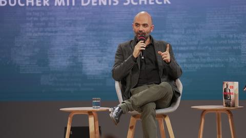 Italiens Mafia-Enthüllungsautor Roberto Saviano sitzt auf der Bühne, neben ihm steht sein Buch. 