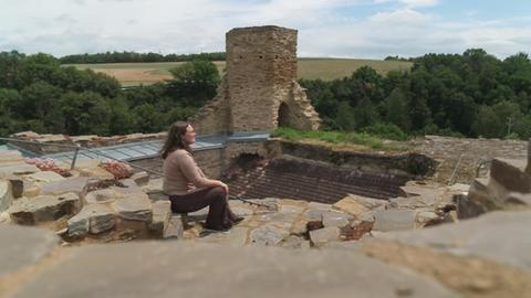 Lauren Liss sitzt auf den Mauern der Burgruine und schaut ins Tal.