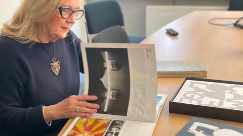 Ein blonde Frau mit Brille blättert in einem Fotoalbum