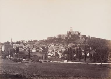 Schwarz-Weiß-Foto, es zeigt einen Hügel, auf dem eine Burg liegt. Am Fuß des Hügels liegt eine Siedlung.