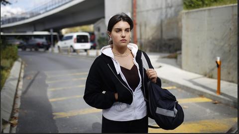 Eine junge Frau läuft mit einer Sporttasche eine Straße in Berlin entlang. 