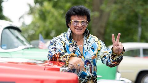 Ein Besucher des Elvis-Festival lehnt im Kostüm an seinem Oldtimer.