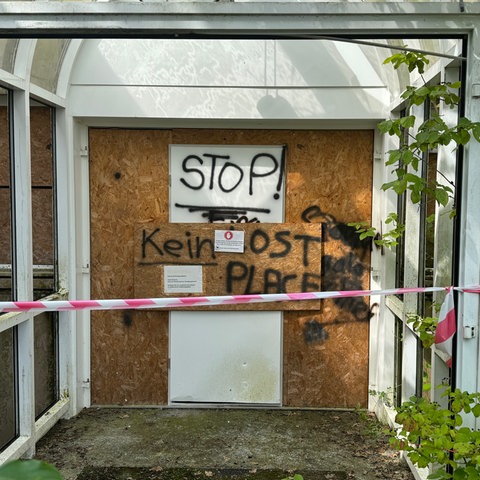 Das Bild zeigt den Eingang der leerstehenden ehemaligen ESOC-Bodenstation in Michelstadt. Die Tür ist mit einem Korkbrett vernagelt, davor ist ein rot-weißes Absperrband gespannt. An der Tür steht: Stop! Kein Lost Place.