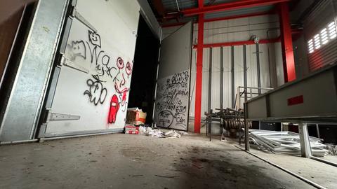 Das Bild zeigt die leerstehende ehemalige ESOC-Bodenstation in Michelstadt: eine große leere Halle mit Graffiti an den Wänden. Auf dem Boden liegen Müll und zurückgelassene Kartons.