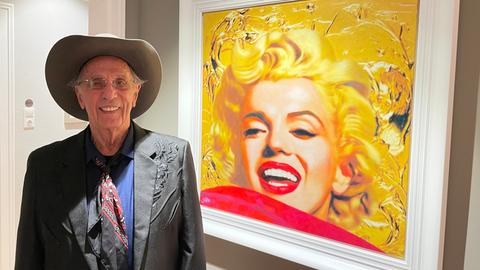 Mann mit Cowboyhut vor einem Gemälde von Marilyn Monroe