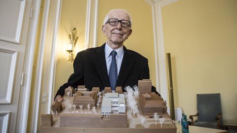 Ein älterer Mann hält ein Architektur-Modell in den Händen