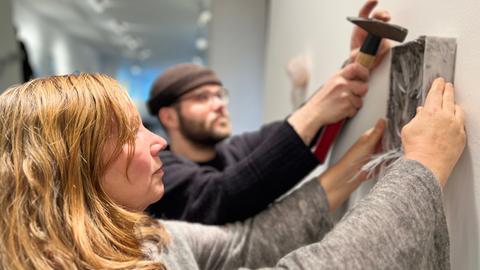 Zwei Menschen hängen ein Bild an die Wand