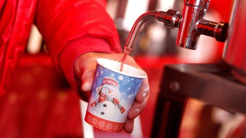 Ein Mann zapft Glühwein in einen Pappbecher