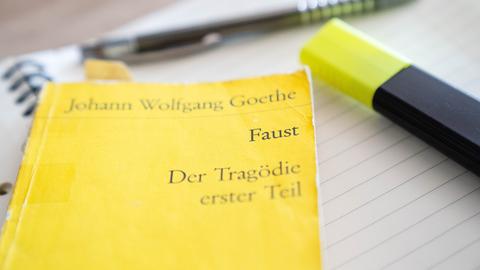Ein Textmarker und eine Ausgabe "Faust - Der Tragödie erster Teil" liegen auf einem Schreibblock.