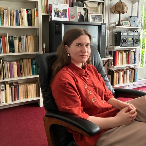 Das Bild zeigt Hafen der Zuflucht-Stipendiatin Victoria Feshchuk vor einem Bücherregal, das eine gesamte Wand einnimmt. Sie lächelt in die Kamera.