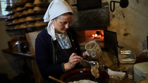 Eine Frau mit Kopftuche bäckt Brot