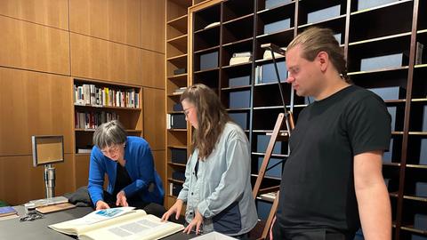 Das Bild zeigt eine Ausstellungsansicht von "Zeitzeugen? Ein Erinnerungslabor" im Historischen Museum Frankfurt. Zu sehen sind zwei nachgebaute Paternoster, im Hintergrund läuft eine Foto-Show auf einer Leinwand.