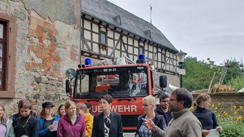 Menschen stehen in einer Burganlage vor einem Feuerwehr-Auto.