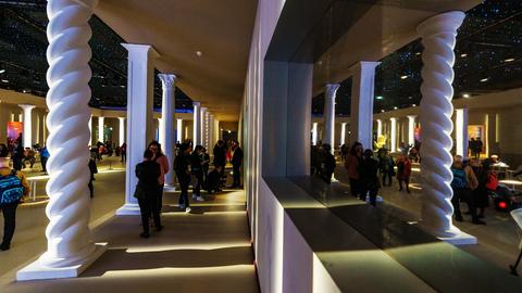 Das Bild zeigt den Ehrengast-Pavillon von Buchmesse-Gastland Italien. Zu sehen ist eine spärlich beleuchtete Halle mit weißen Säulen. Dazwischen stehen Menschen, die sich unterhalten.