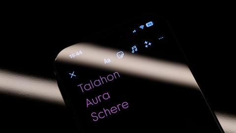 Die Top-3-Jugendwörter "Talahon", "Aura" und "Schere" sind auf dem Display eines Smartphones zu sehen. 