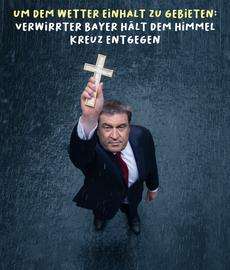 Markus Söder reckt ein Holz-Kreuz in den Himmel und blickt nach Oben. Darüber steht: "Um dem Wetter Einhalt zu Gebieten: Verwirrter Bayer hält dem Himmel Kreuz entgegen."