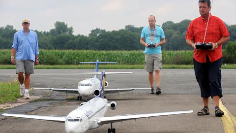 Modellflieger steuern ihre Flugzeugmodelle über eine Start- und Landebahn.